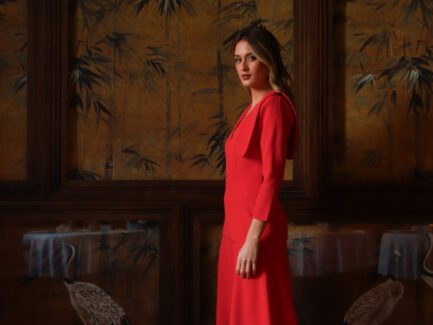 Vista de perfil del vestido de invitada Zaira rojo con solapas de raso y falda midi